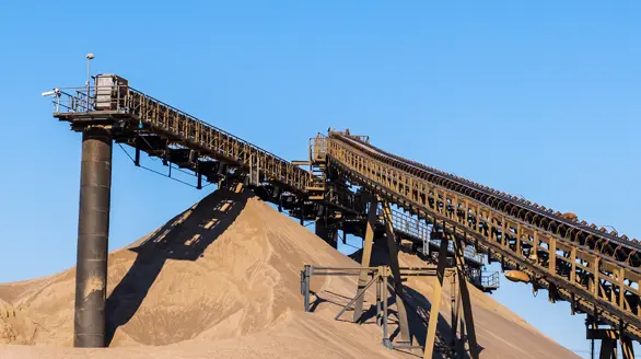 Sistema de cintas transportadoras industriales procesando montañas de agregados en una grancera
