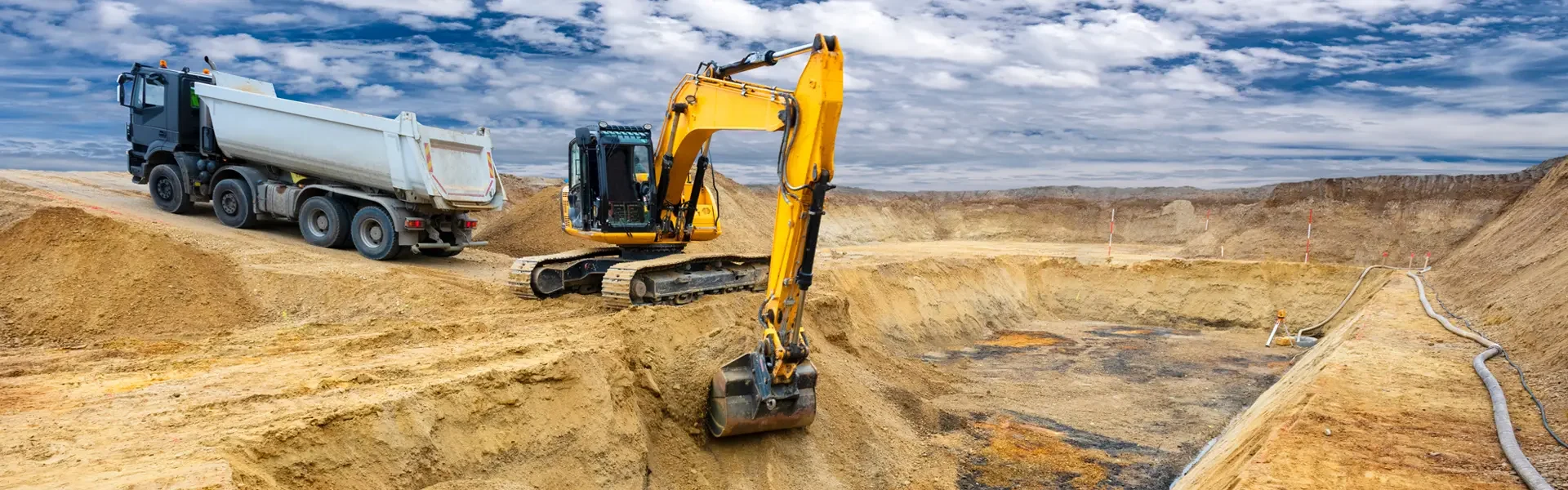 Lo que debes poner: Excavadora y camión articulado operando en un proyecto de movimiento de tierra continuo.