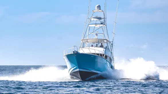 Yate de pesca deportiva navegando a alta velocidad en mar abierto, rompiendo las olas.